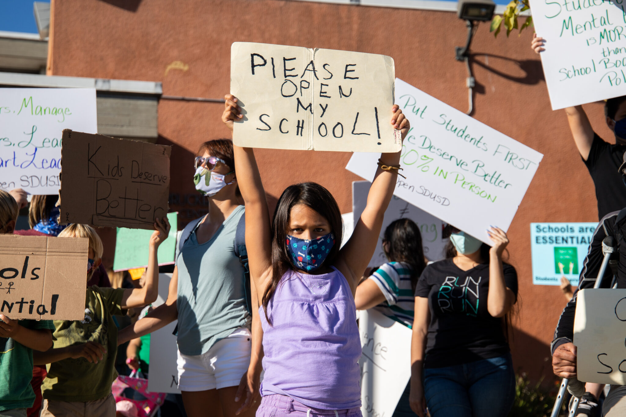 A student protests school closures at San Diego Unified with a group of parents and other students