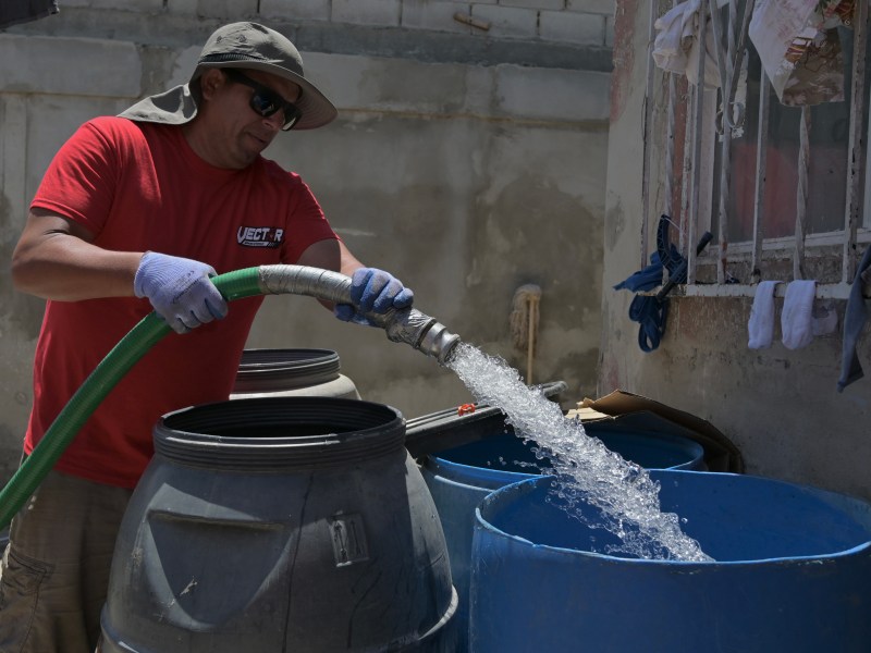 A worker with CESPE filles up a large container with water on Friday, July 1, 2022. / Photo by Carlos A. Moreno for Voice of San Diego