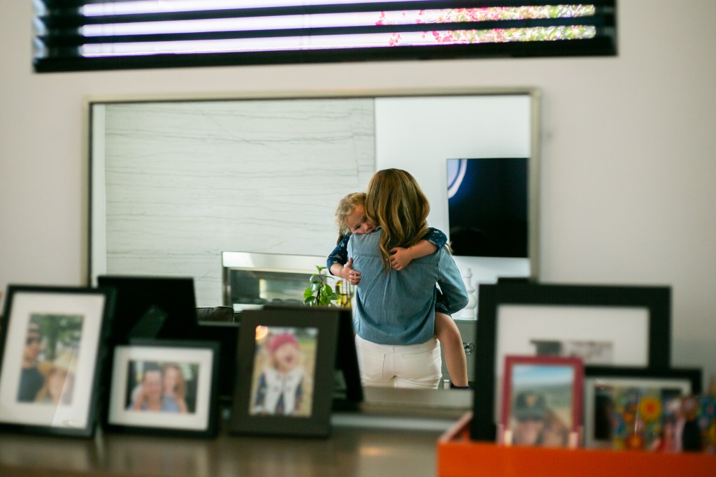 Shana Hazan, SDUSD board candidate carries her daughter who had just come home from school in their home in San Diego, CA.