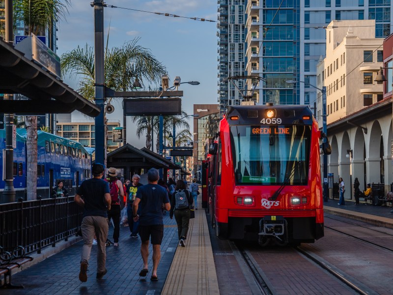 People walk near the Green Line trolley at the Santa Fe Depot in downtown on Oct. 4, 2022.