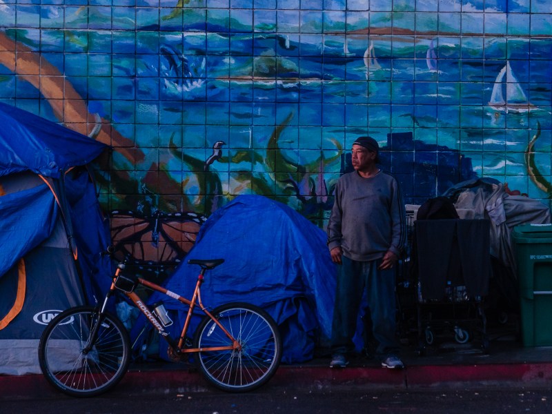 A man stands near his tent on Commercial Street Street in downtown on March 30, 2023.