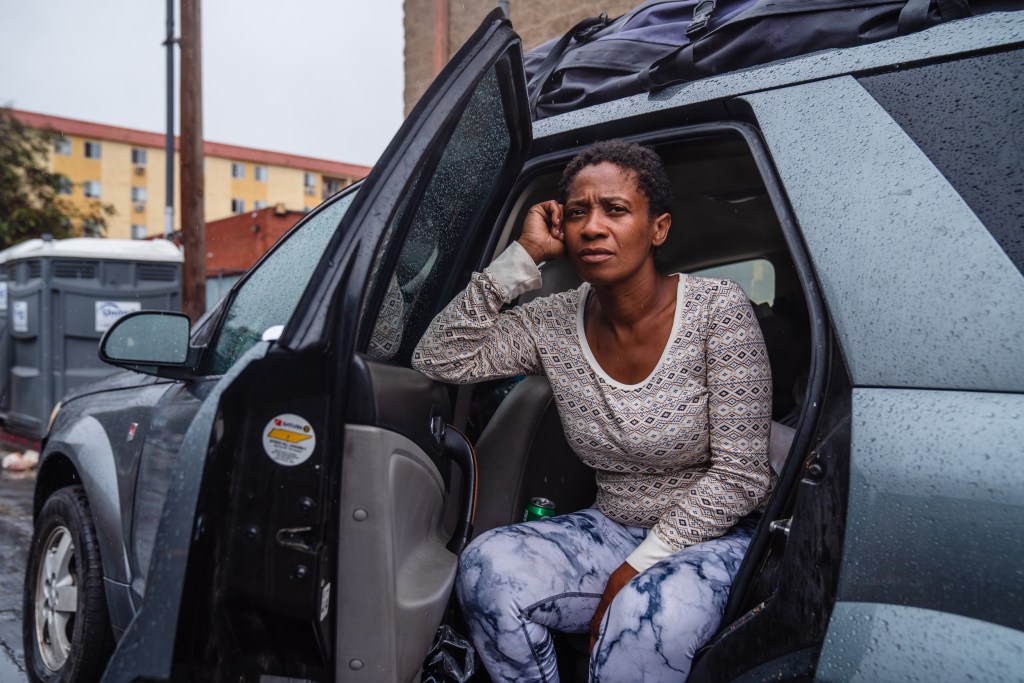 Naomi Early from Alabama takes shelter in her car while it rains in downtown on Aug. 20, 2023. Early slept at Father Joe's the night before and is hoping to stay in a shelter tonight. Being from the South she says she has experience with hurricanes and tornadoes.