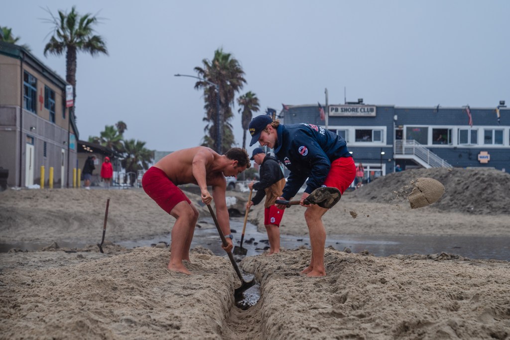 Lifeguards separate the sand so water can go through into the ocean in Pacific Beach on Aug. 20, 2023.